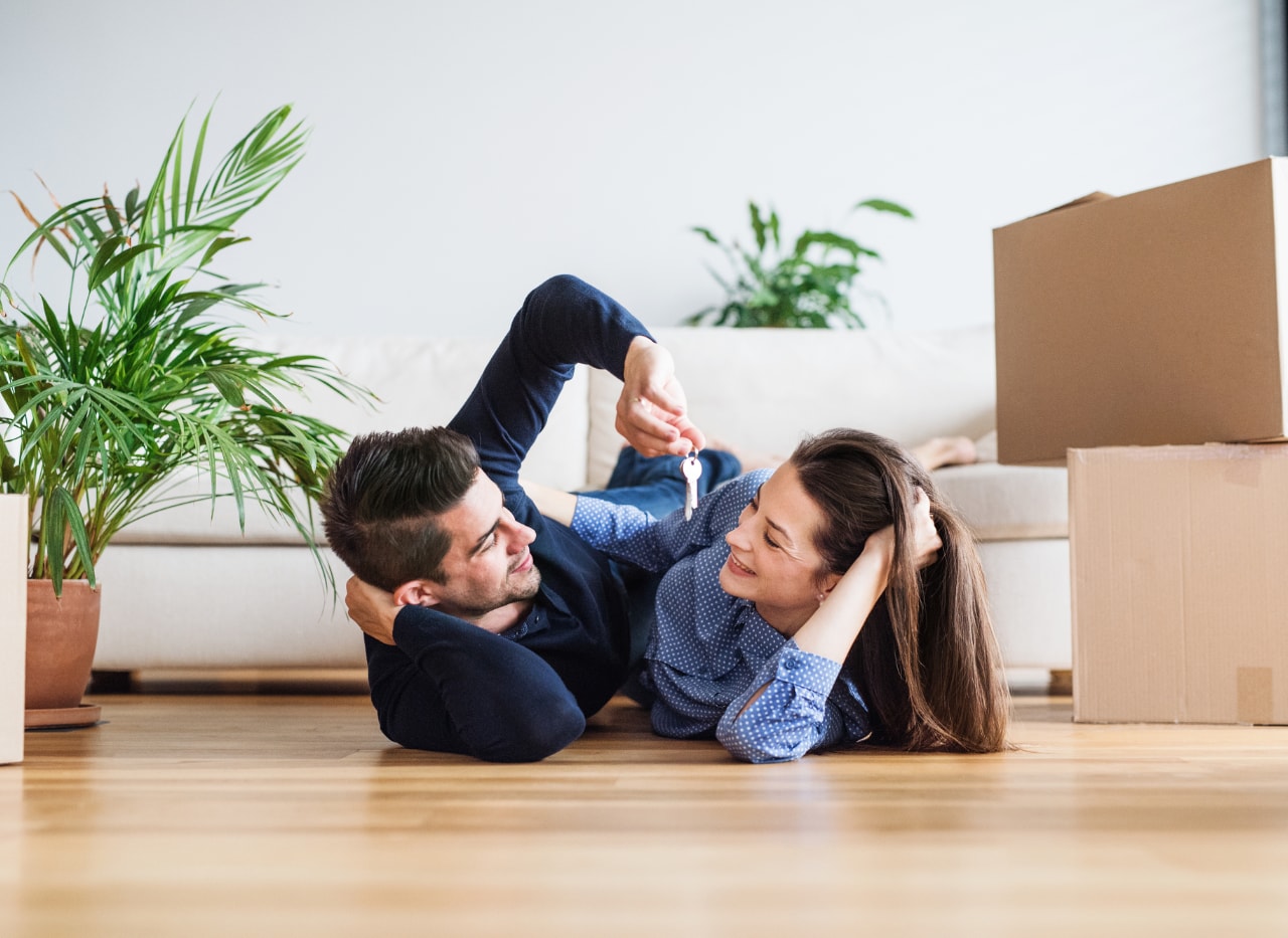 Et par der ligger med hinanden, hvor manden holder et sæt nøgler mellem dem.