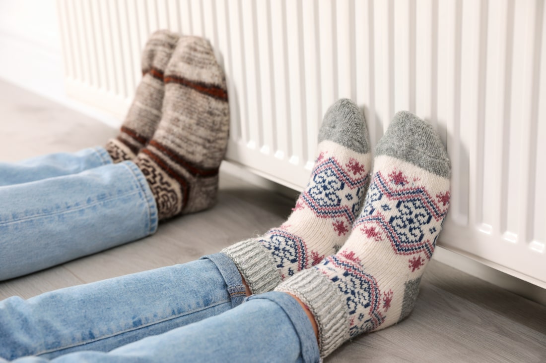 To personer med uldsokker som varmer der fødder på en radiator.